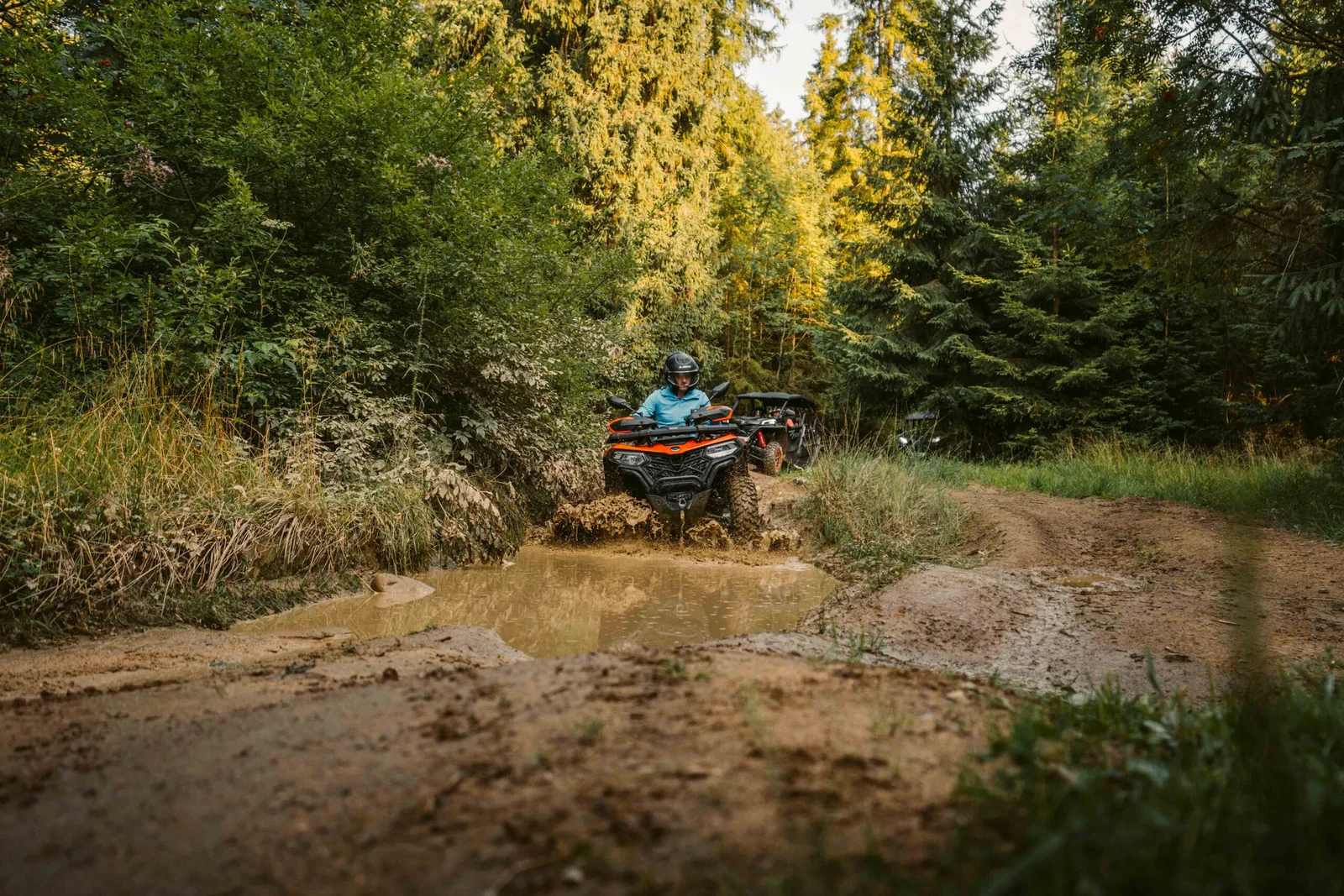 ZDJ-01853 – pomarańczowy quad wjeżdżający w dużą błotnistą kałużę na leśnej trasie