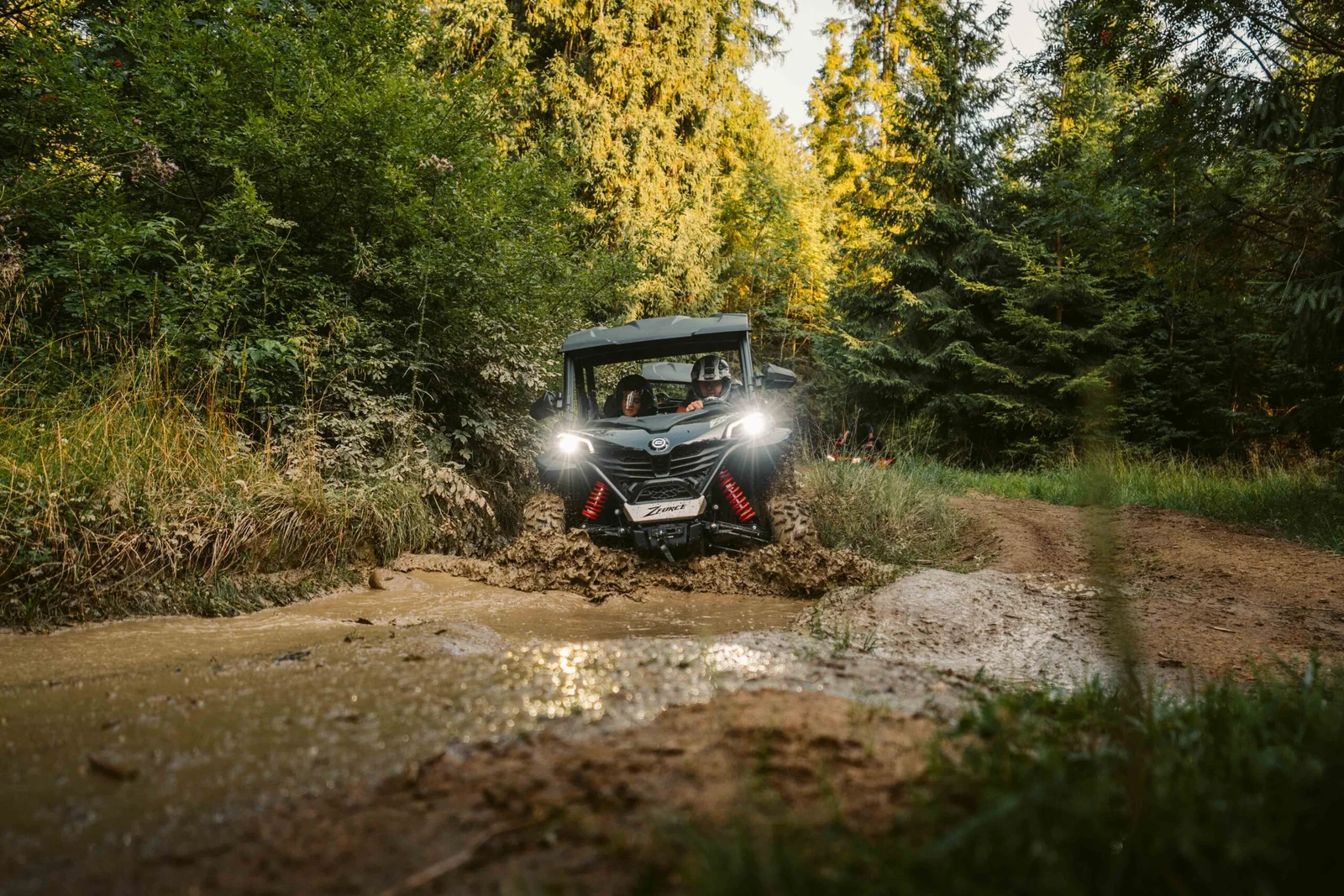 ZDJ-01895 – buggy z pasażerami wjeżdżające w głęboką błotnistą kałużę na leśnej trasie