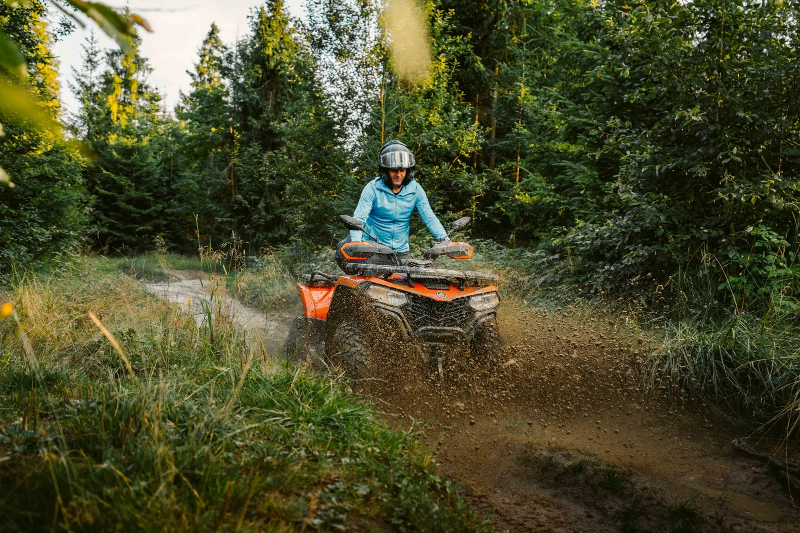 ZDJ-01955 – pomarańczowy quad dynamicznie przejeżdżający przez błoto na leśnej trasie