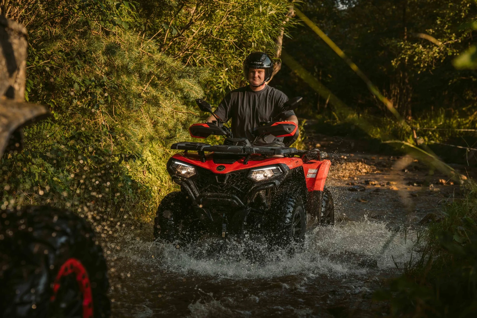 ZDJ-02190 – czerwony quad z kierowcą przejeżdżający przez leśny strumień