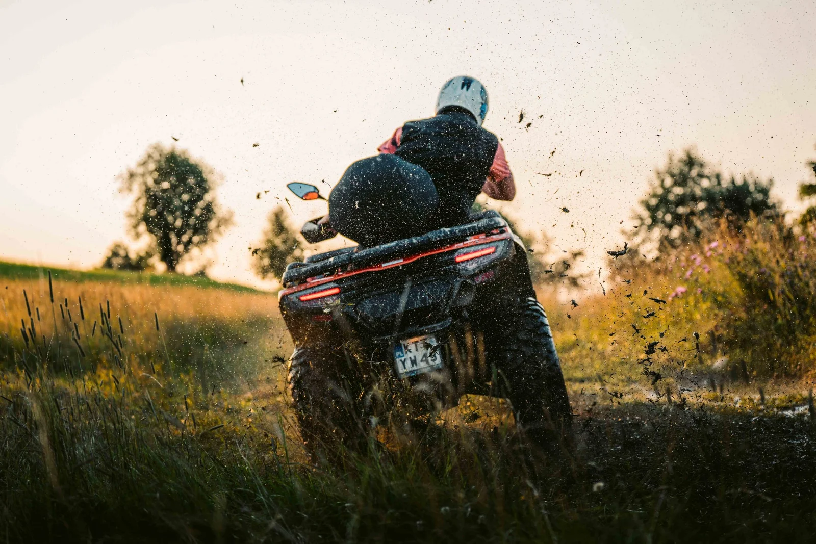 ZDJ-02390 – quad widziany od tyłu podczas agresywnej jazdy przez błoto o zachodzie słońca