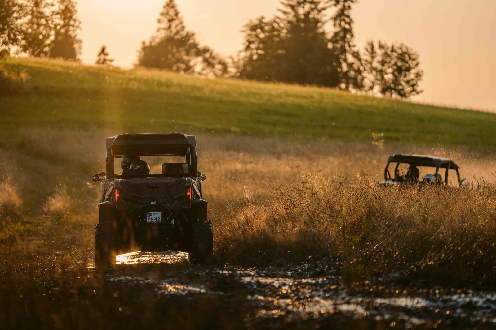ZDJ-02578 – buggy UTV jadące tyłem przez błotnistą trasę o zachodzie słońca